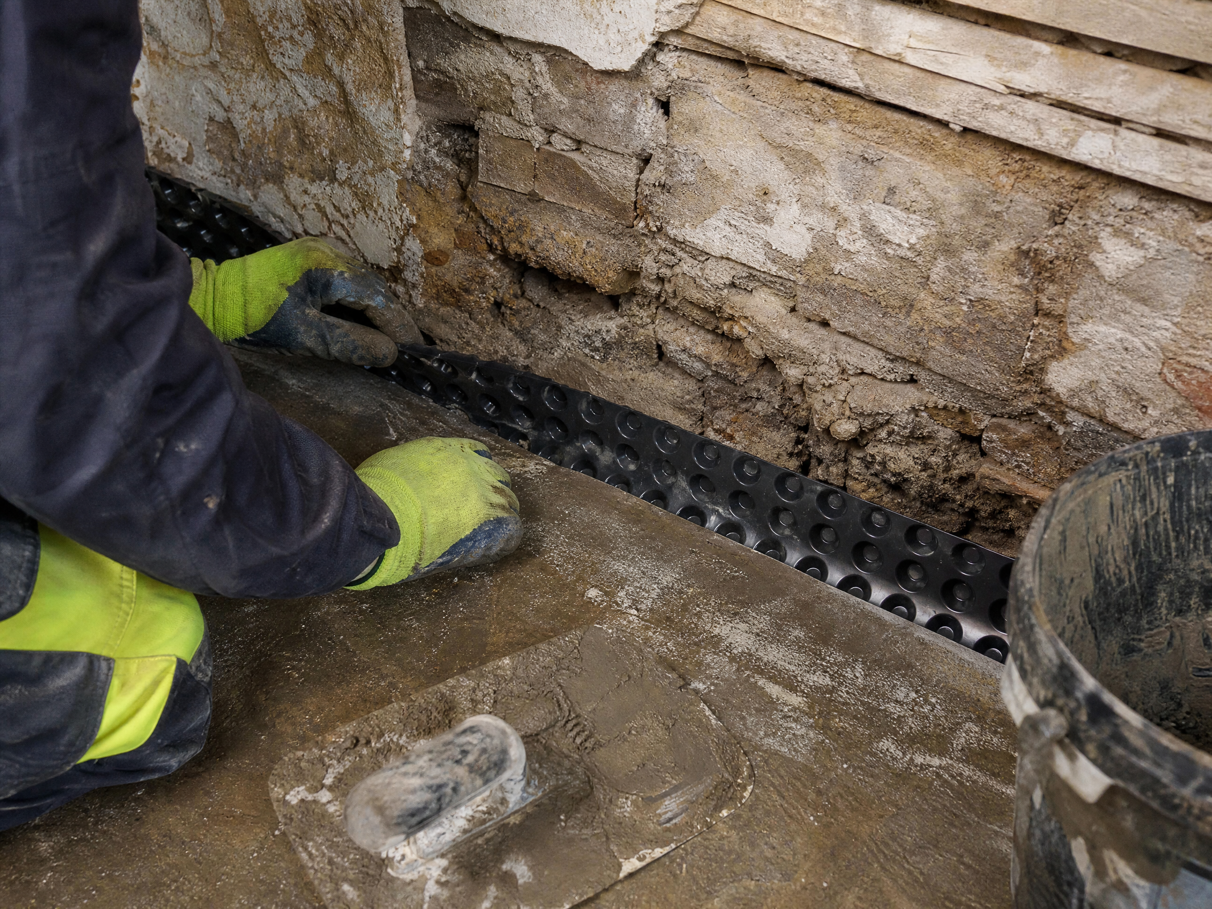 Professional installer carrying out basement waterproofing in a UK residential property